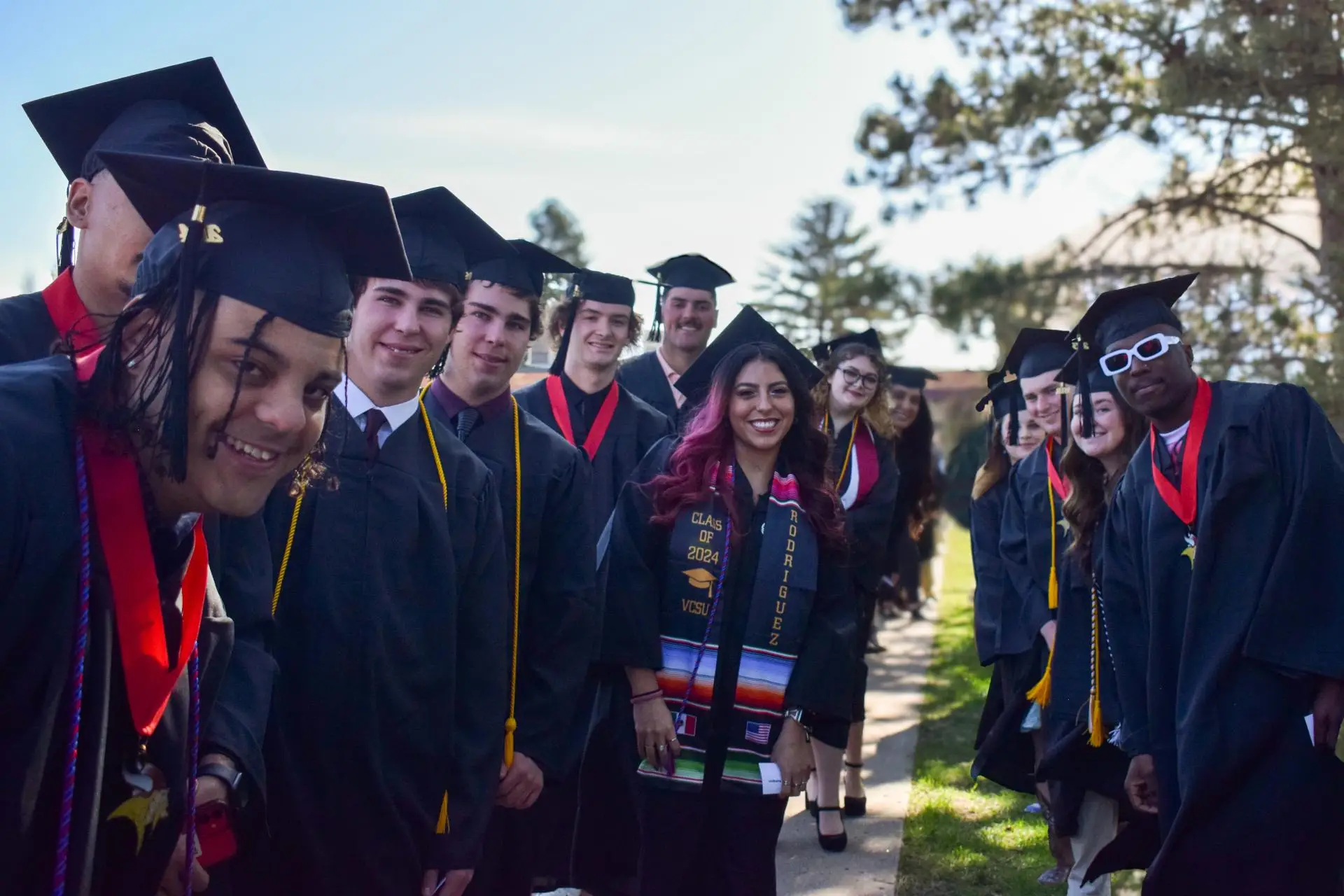 graduates in caps and gowns smiling at camera